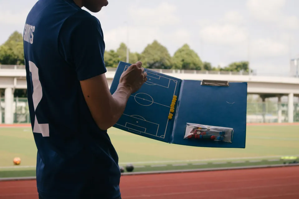 Trainer mit einer Taktiktafel am Spielfeldrand
