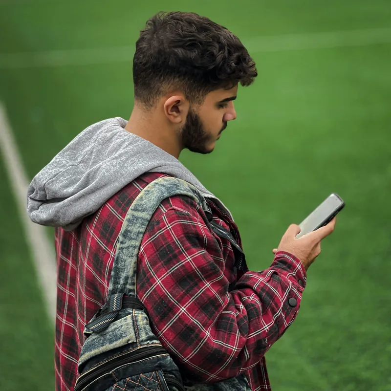 Trainer am Spielfeldrand schaut auf sein Handy